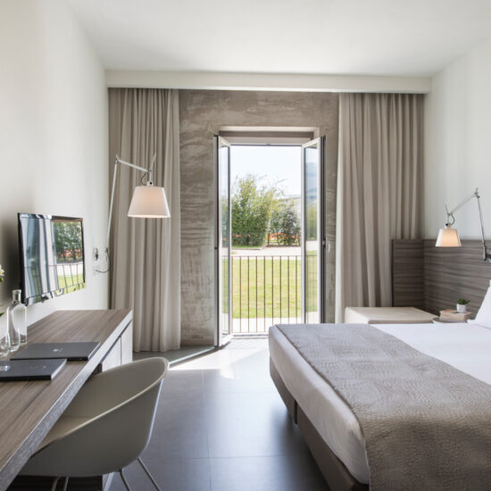 Camera Garden con letto bianco, testata in legno, corridoio con armadio e lampade di design a braccio sulle pareti