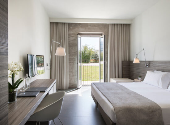 Camera Garden con letto bianco, testata in legno, corridoio con armadio e lampade di design a braccio sulle pareti