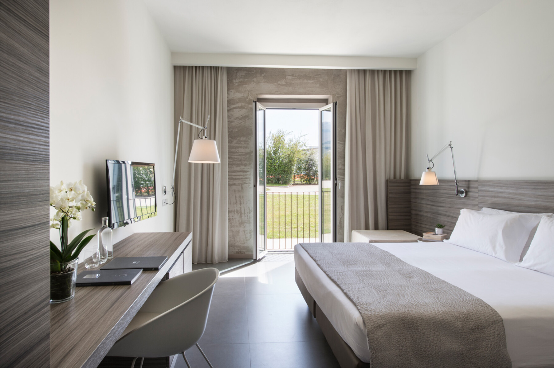 Camera Garden con letto bianco, testata in legno, corridoio con armadio e lampade di design a braccio sulle pareti